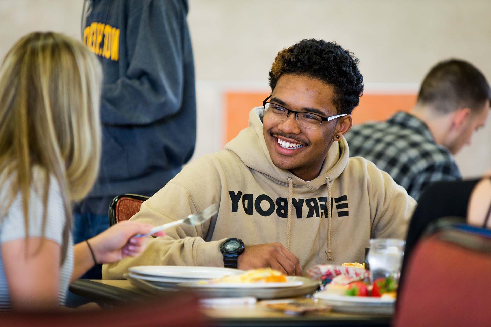 Student smiling while dining in the cafeteria.